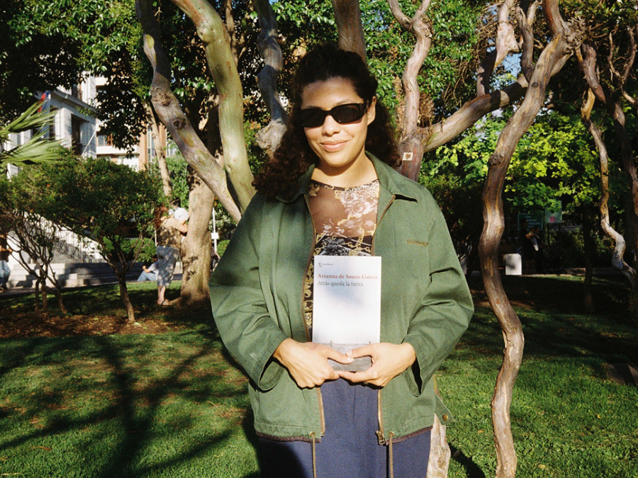 La escritora Arianna de Soussa-García sostiene su libro Atrás queda la tierra en un parque al aire libre.